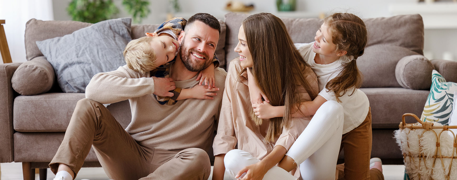 Lachende Familie im eigenen Wohnzimmer mit den Kindern